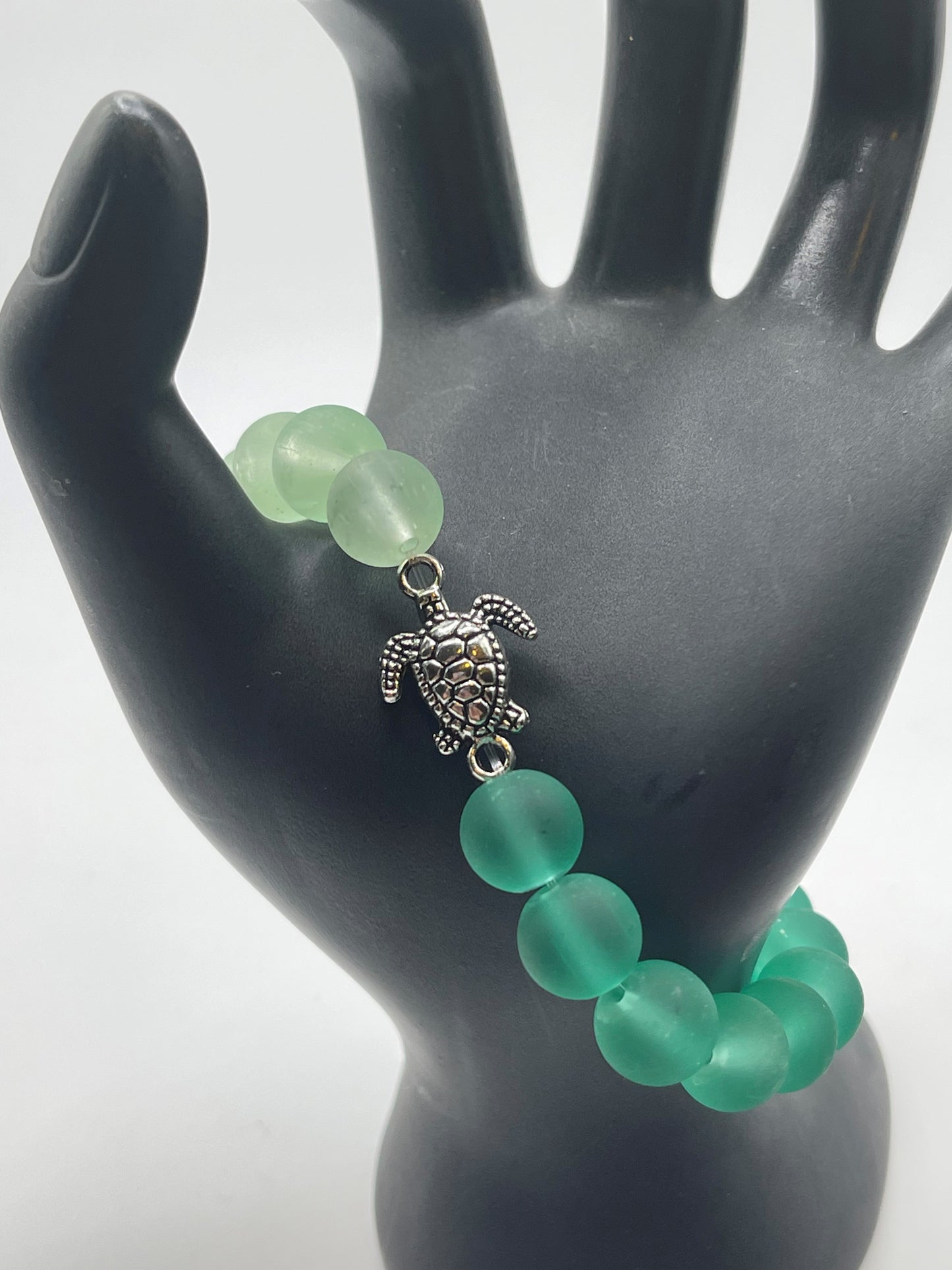 Sea turtle with green sea glass bracelet.